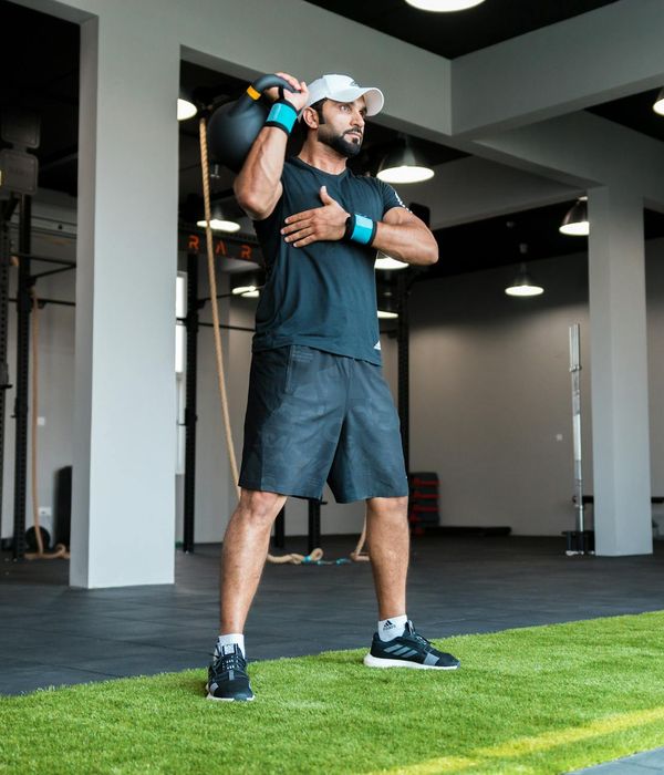 Man performing a dynamic strength exercise in a modern gym.